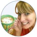 Emma, (a smiling white woman with blonde hair and blue eyes) is holding a green mug filled with hot chocolate topped with mini marshmallows. The mug features the Disney character Dopey from Snow White and the word "DOPEY" in bold yellow letters. Emma is wearing a red top and appears cheerful and relaxed. The image is cropped into a circular frame with a thin blue border.
