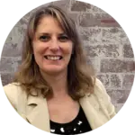 Virtual Assistant for Small Businesses. Image of Emma (blonde white female) smiling into the camera wearing a black top and cream jack, with a rustic brick wall background.